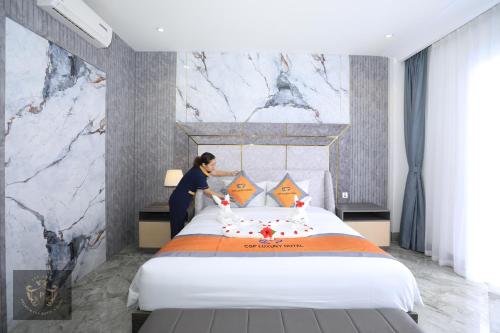 a woman making a bed in a hotel room at Premium CGP Hotel Hoi An in Hoi An
