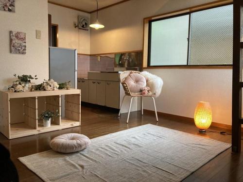 sala de estar con alfombra, silla y ventana en コテージ上浦, en Azamui