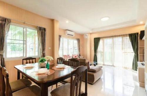 a living room with a table and a dining room at Near airport cozy home in Chiang Mai