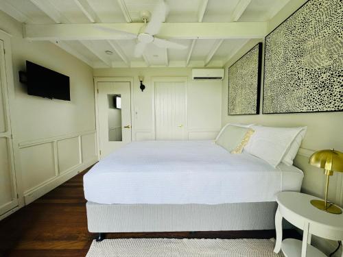 a white bedroom with a white bed and a table at Misty Valley Cottage in Mapleton