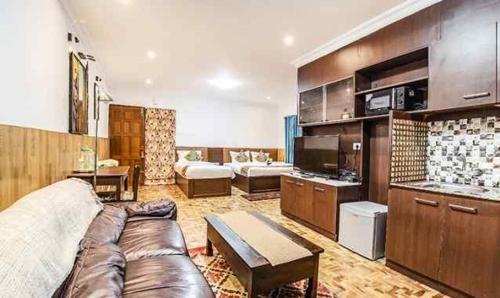a large living room with a couch and a kitchen at KevinsBearsholaResidency in Kodaikānāl