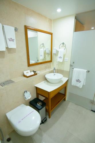a bathroom with a sink and a toilet and a mirror at Classic Grande,a Member of Radisson in Imphal