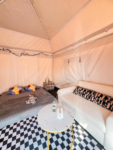 una habitación con sofá y mesa en una tienda de campaña en หลานย่าโฮมสเตย์ บางตะบูน, en Ban Khung Tamnak
