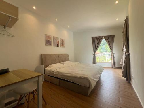 a bedroom with a bed and a desk and a window at Hillview Ipoh in Ipoh