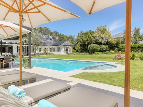 a swimming pool with an umbrella next to a house at Russet Rise, Adults Only in Cape Town