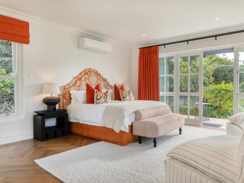 a bedroom with a bed and a chair and windows at Russet Rise, Adults Only in Cape Town