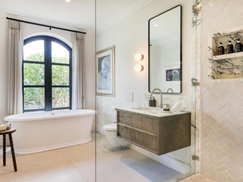 a bathroom with a tub and a sink and a mirror at Russet Rise, Adults Only in Cape Town