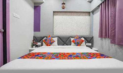 a bedroom with a large white bed with colorful pillows at FabHotel Imperial Suites in Nagpur