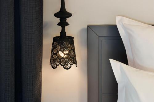 a black lamp hanging on a wall next to pillows at Hotel Mademoiselle in Paris