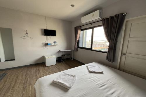 a bedroom with a bed and a window and a television at Blue26 in Ban Wat Sala Daeng