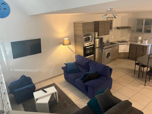 un salon avec un canapé bleu et une cuisine dans l'établissement Maison entière avec spa privatif Bulle sur Sye en Drome, à Aouste-sur-Sye