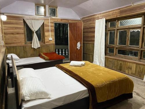 a bedroom with two beds and two windows at Aranya Baas By StayApart in Sukhia Pokhari