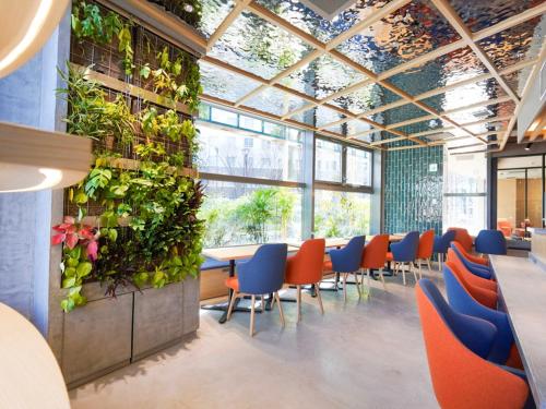 a restaurant with tables and chairs and plants on the wall at The GALA Hotel Umeda in Osaka