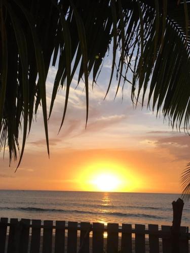 a sunset over the ocean with a wooden bench at Sakâ Sakâ Beach House in Sipalay
