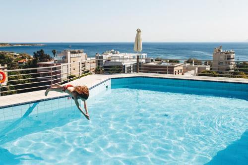 een persoon die bovenop een gebouw in een zwembad springt bij Emmantina Hotel in Athene