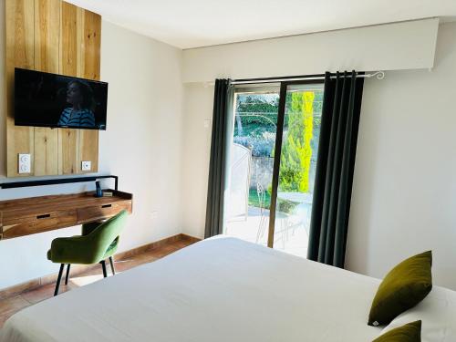 a bedroom with a bed and a desk and a window at Hôtel Le Colombier in Moustiers-Sainte-Marie