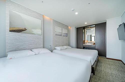 two beds in a hotel room with a tv at Griffinbay Hotel in Busan
