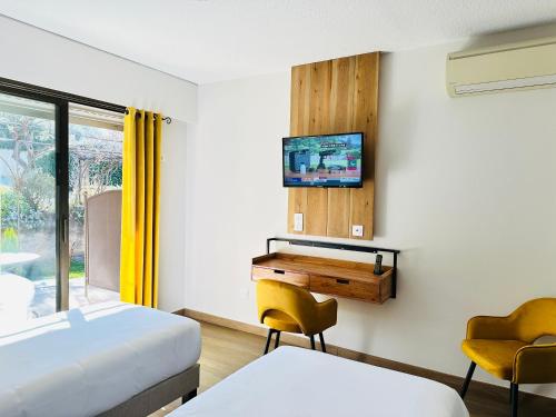 a bedroom with a bed and a desk and a tv at Hôtel Le Colombier in Moustiers-Sainte-Marie