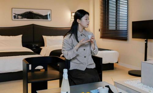 a woman standing in a hotel room looking at her cell phone at Aank Hotel and Spa Jongno Unni in Seoul