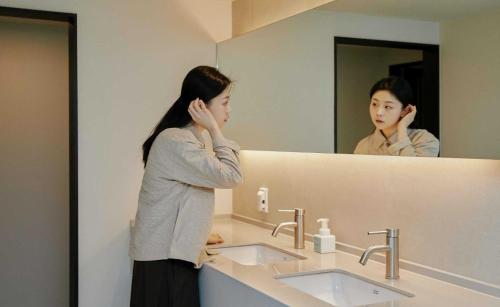 a woman standing in front of a bathroom mirror at Aank Hotel and Spa Jongno Unni in Seoul