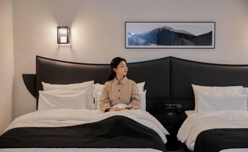 a woman sitting on a bed in a hotel room at Aank Hotel and Spa Jongno Unni in Seoul