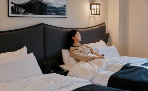 a woman sitting on a bed in a hotel room at Aank Hotel and Spa Jongno Unni in Seoul