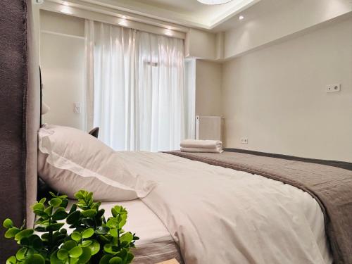 a bedroom with a bed with white sheets and a window at T seaside cozy APT in Athens