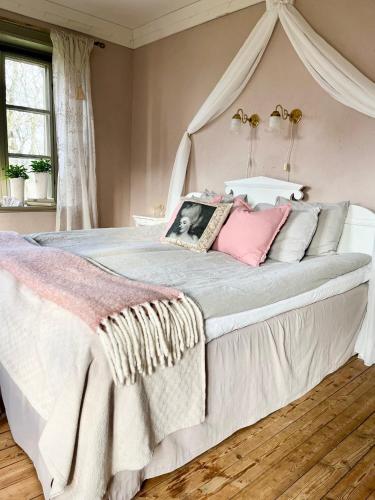a bedroom with a large white bed with pink pillows at Lydde Gård in Kinna