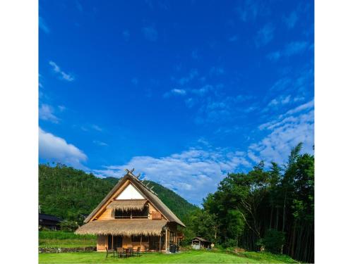 a house with a thatched roof on a green field at Miyama KAYA Villa in Nantan city