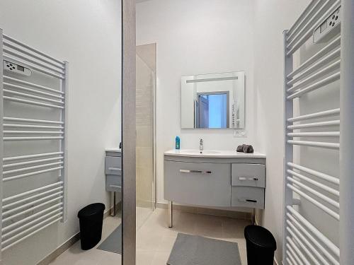 une salle de bain blanche avec un lavabo et un miroir dans l'établissement Le Saint Roch, Proche Gare et Comédie, à Montpellier