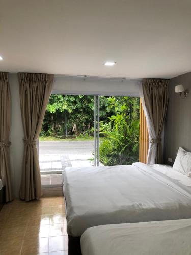 a bedroom with two beds and a large window at พิชชาวรี รีสอร์ท in Ban Si Thep (2)