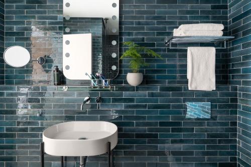 a bathroom with a white sink and blue tiles at Hotel Bazaar - Fattal Colors in Tel Aviv