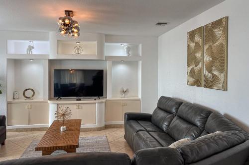 a living room with a leather couch and a flat screen tv at ESCAPADA AL MAR Departamento el Rosarito in Rosarito Beach