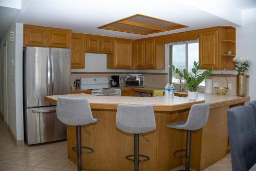 a kitchen with wooden cabinets and a island with bar stools at ESCAPADA AL MAR Departamento el Rosarito in Rosarito Beach
