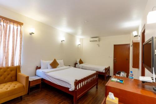 a hotel room with two beds and a chair and a desk at Lake View Resort in Pokhara