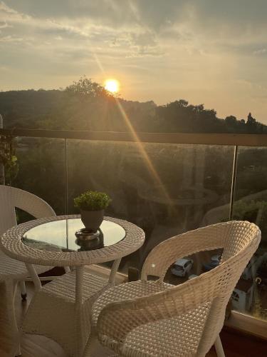 a table and chairs on a balcony with the sunset at Abode 3-2 bhk attic private terrace Siolim Marna in Camorlim