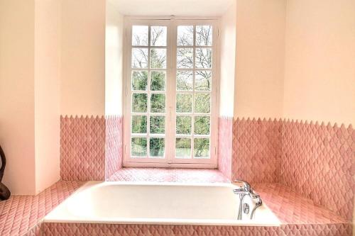 une baignoire dans une salle de bain avec une fenêtre dans l'établissement Maison de famille vallée de Chevreuse, à Saint-Forget