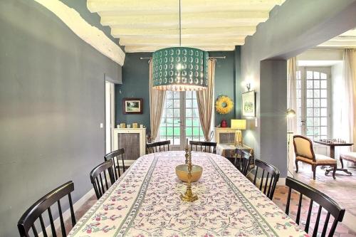 une salle à manger avec une table, des chaises et un lustre dans l'établissement Maison de famille vallée de Chevreuse, à Saint-Forget