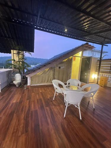 a patio with a table and chairs on a wooden floor at Abode 3-2 bhk attic private terrace Siolim Marna in Camorlim