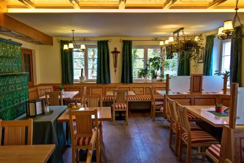 um restaurante com mesas e cadeiras de madeira e janelas em Landgasthof zum Betenmacher em Thalgau