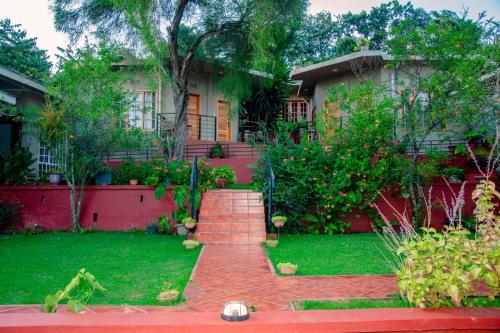 a house with a brick walkway in front of a yard at Babylon Lodge in Marangu