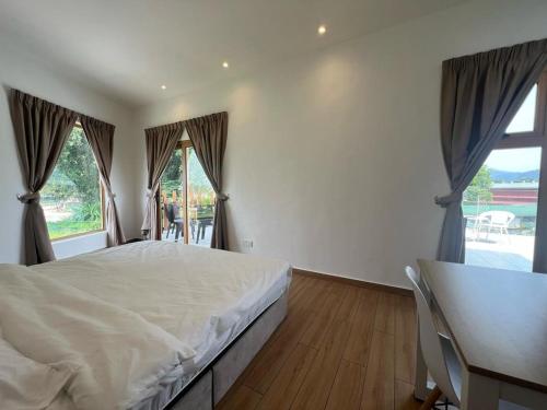 a bedroom with a bed and a desk and windows at Hillview Ipoh in Ipoh