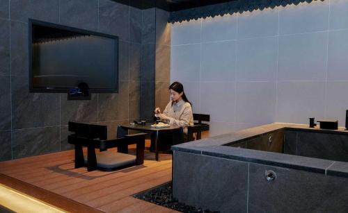 a woman sitting at a table in a room with a tub at Aank Hotel and Spa Jongno Unni in Seoul