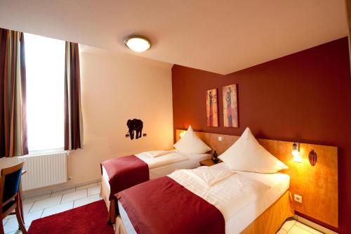 a hotel room with two beds and a cow on the wall at Hotel Alt Speyer in Speyer