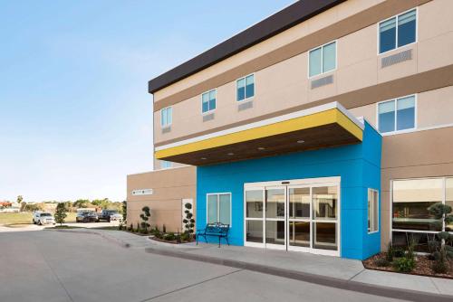 a building with a blue bench in front of it at Days Inn by Wyndham Beaumont West I-10 Walden in Beaumont