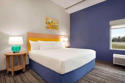 a bedroom with a large bed with a blue wall at Days Inn by Wyndham Beaumont West I-10 Walden in Beaumont