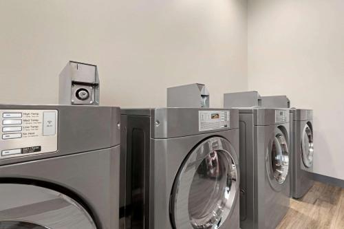 three washing machines are in a laundry room at Days Inn by Wyndham Beaumont West I-10 Walden in Beaumont