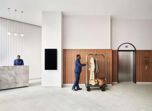 a man pushing a luggage cart in a lobby at Hyatt House London Stratford - Aparthotel in London