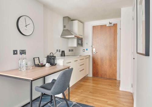 a kitchen with a table and a clock on the wall at Hyatt House London Stratford - Aparthotel in London