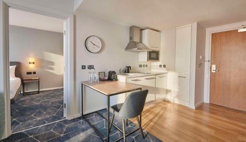 a kitchen with a table and a clock on the wall at Hyatt House London Stratford - Aparthotel in London